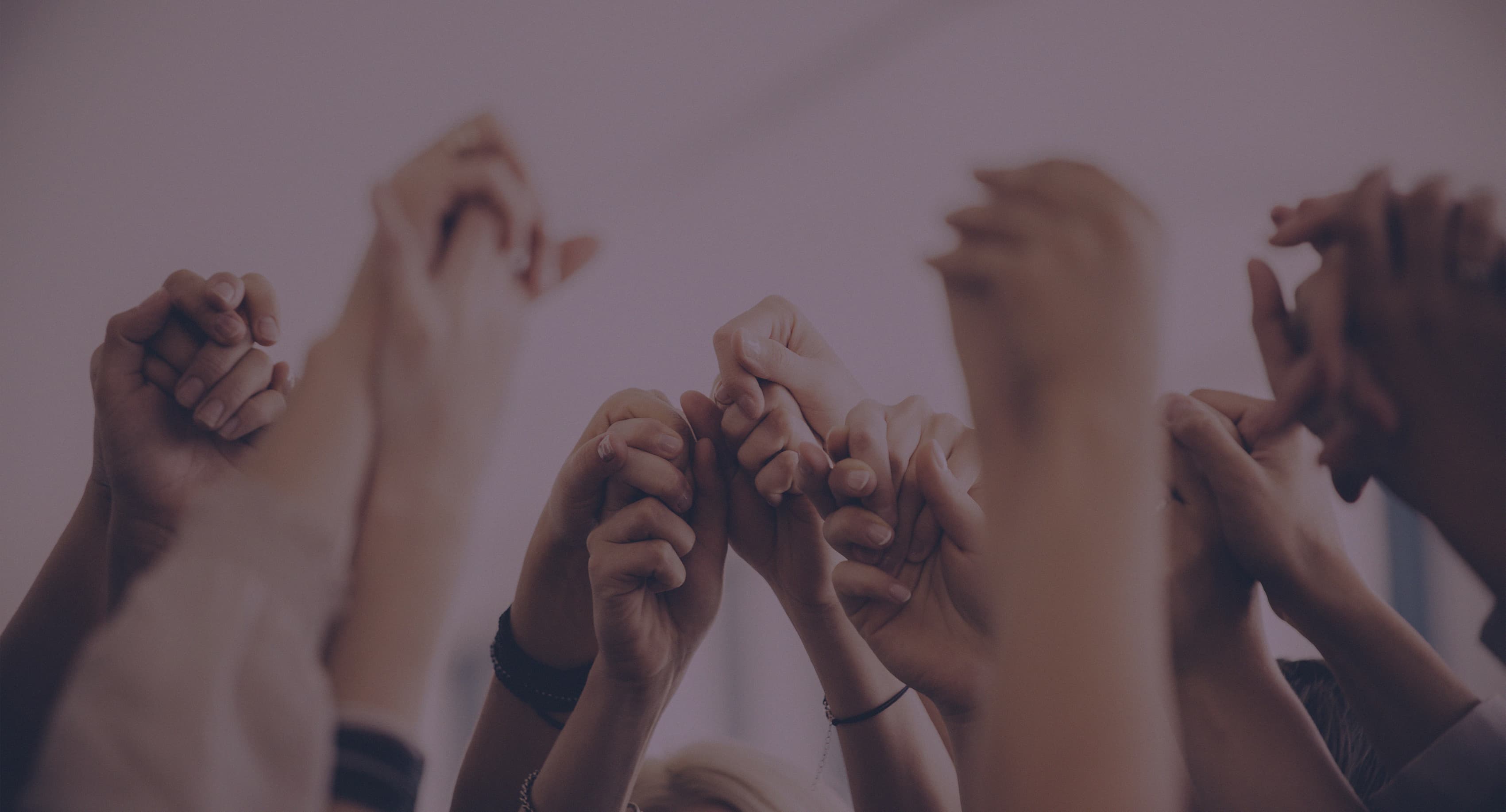 people holding hands above heads in a circle